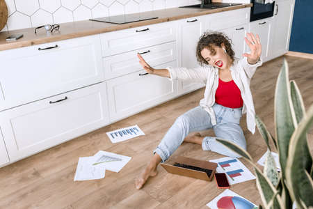 Joyful beautiful business woman using laptop, smiling, sitting on the floor at home. Attractive...