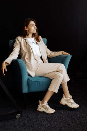 Cheerful business woman sitting in the studio, laughing, talking to someone in the room, looking...