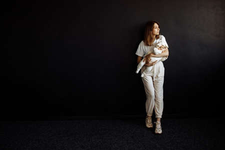 Happy mom is photographed with her little daughter in the studio. She is holding the baby in her...