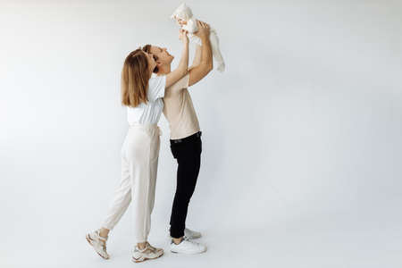 Portrait of a young family, with a little baby in her arms. Mom and Dad beautifully pose for a...