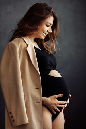 Portrait of beautiful fashion woman hug own pregnant tummy, expect for a first baby, happy lady excited about maternity, enjoy pregnancy, motherhood concept. high quality photoの写真素材