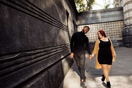 Joyful couple walking at the city, beautiful woman dancing with attractive African American man, adorable wife having fun with charming husband, happy moments concept. high quality photoの写真素材