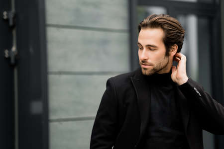 Handsome stylish man is working as a model for fashion magazine, posing for the photo. Successful business male in classic fashion suit is looking directly at the camera, showing self confidence.の写真素材