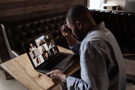 Exhausted tired African American businessman sitting at work desk with closed eyes, falling asleep, overworked young man, unmotivated student sleeping at workplace, boring routine workの写真素材
