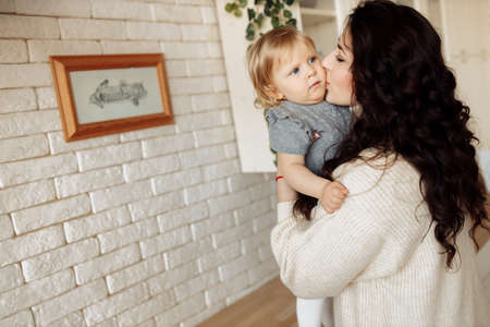 Happy mother hold cute baby girl in loving arms, pretty woman enjoy tender moments with little daughter, Christmas celebration at home, toddler first winter holidays concept. High quality photoの写真素材