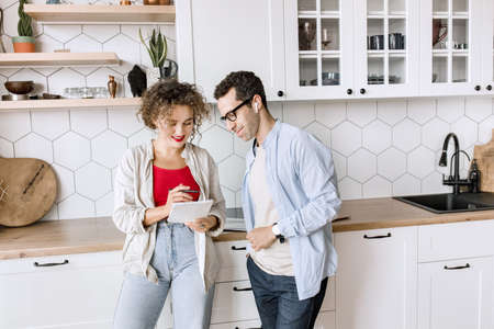 Young and smart stylish business partners are working on a project in a modern office, discussing ideas. Happy colleagues studying financial charts, using laptop, talking about new strategy, smilingの写真素材