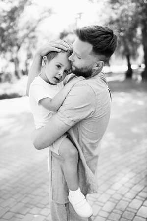 Handsome man with little boy at the park, lovely son sitting on fathers arms, smiling, dad and toddler spend time together, enjoy tender family moments, parenthood concept. high quality photoの写真素材