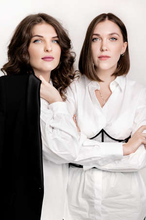 Two stylish women in formal clothes looking at the camera, showing their confidence . Serious business female standing in fashion outfits, posing to the photographer . high quality photoの写真素材