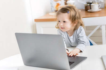 Little beautiful girl study at home while quarantine. Cute child doing homework online sitting in...