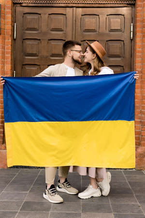 Cute young couple smiling and hugging with flag Ukraine. independence day. Love Ukraine concept. Freedom of Ukraine. Patriot of her country. Pray for Ukraine. stop war. blue yellow. high quality photoの写真素材