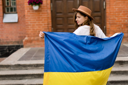 Beautiful girl standing in Ukrainian flag worried about war. Cute woman is feeling emotional pain after reading the news. Freedom and patriot of Ukraine.. Pray for Ukraine. Love Ukraine conceptの写真素材