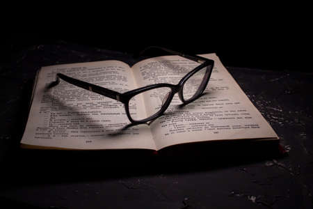 Book and Glasses. Vintage style. Dark background.