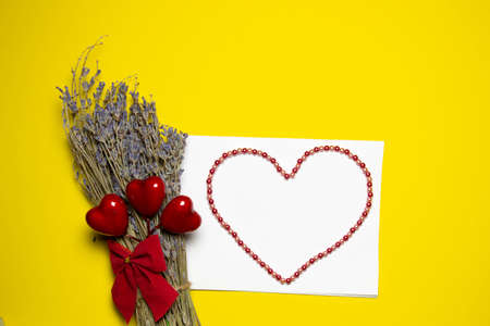 Valentines day congratulation. Red rose and greeting card with heart sign on Yellow background top view copy spaceの写真素材