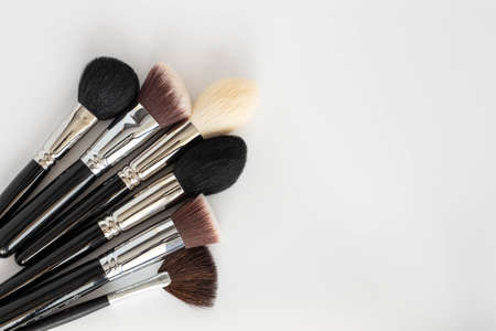 Makeup brushes on white background, top view. Space for text