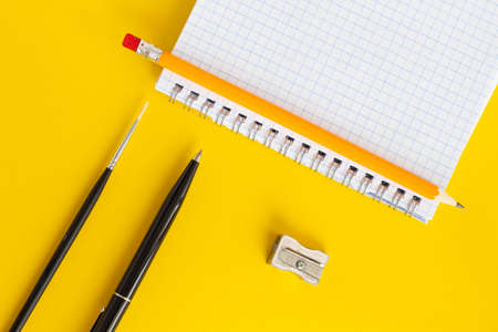 Student concept. Pen, notebook, pencil on a yellow background
