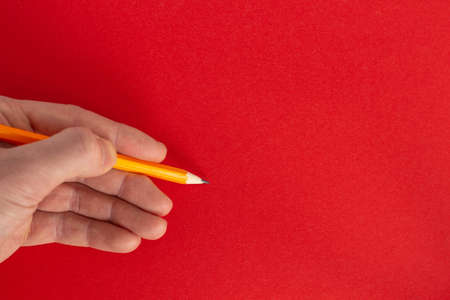 Hand holds a pencil on a colorful backgroundの写真素材