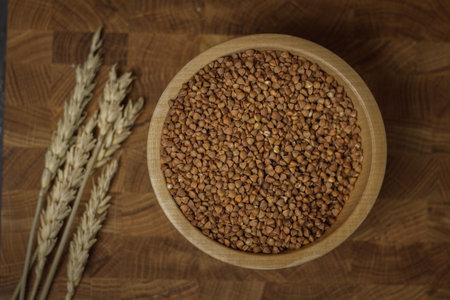 Buckwheat groats in a wooden bowl on a wooden background