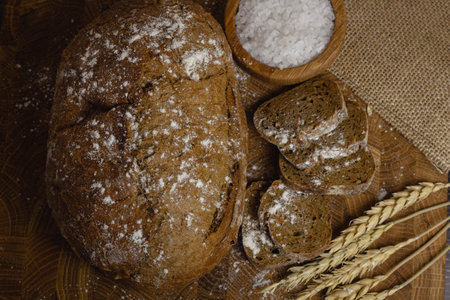 Freshly baked bread and wheat on wooden table. Top view.