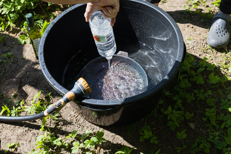 Vinegar is poured from a plastic bottle into a black plastic bucket