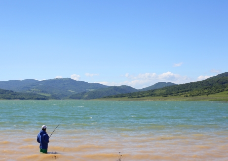 Man fishing at mountainous lakeの写真素材