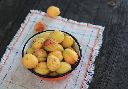 Wild apricots in a bowl on wooden tableの写真素材