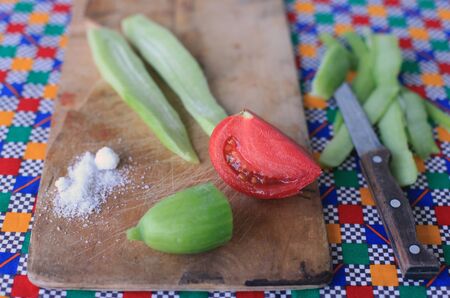 Cutting and pealing vegetables for salad on old wooden cutting board and colorful tablecloth の写真素材