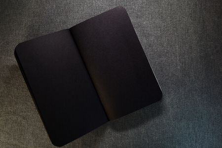 Top view of closed black cover notebook on gray background.