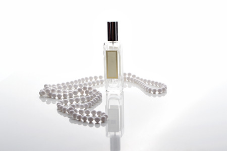 glass perfume bottle on white background with white beadsの写真素材