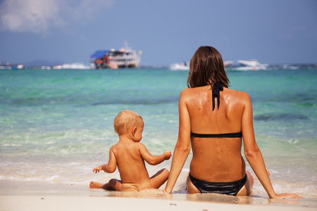 Happy mom and her adorable little daughter during summer vacation on the tropical beachの写真素材