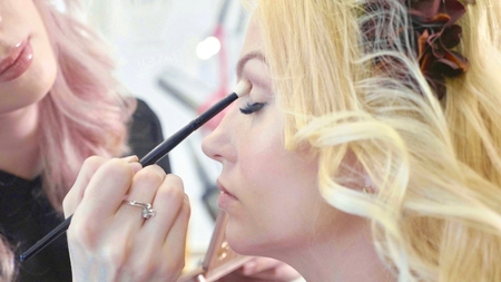 Young makeup artist applying cosmetics on models eyes.の写真素材