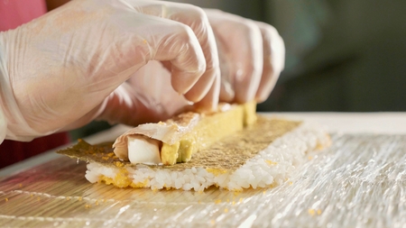 Professional sushi chef preparing roll at commercial kitchen, close-up.の写真素材