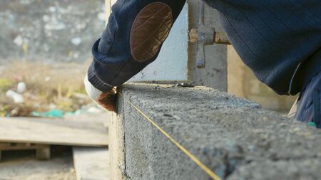 Construction worker builds brick wall, closeup view at construction siteの写真素材