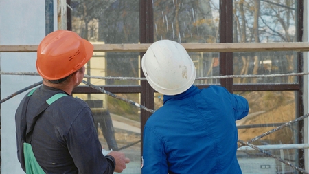 Construction worker and engineer talking at construction site site, rear view.の写真素材