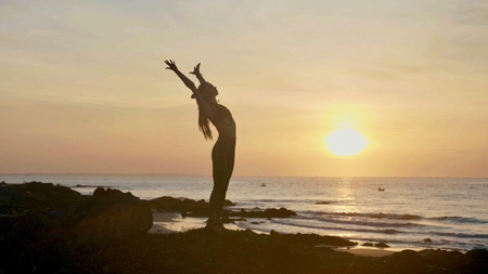 Silhouette yoga practice at sunset. Yong woman doing yoga exercise on the beachの写真素材