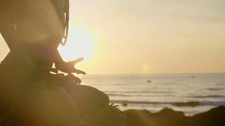 Silhouette yoga practice at sunset. Yong woman doing yoga exercise on the beachの写真素材