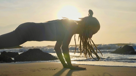 Silhouette yoga practice at sunset. Yong woman doing yoga exercise on the beach