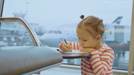 Little baby girl drawing at airport with plane on the backgroundの写真素材