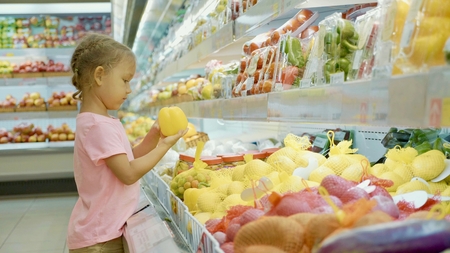 Little cute child girl choosing vegetables in grocery storeの写真素材