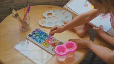 Child girl drawing by watercolor at home.の写真素材