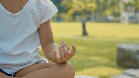 Little child girl meditating in beautiful park with palm trees on the backgroundの写真素材