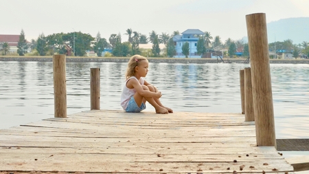 Child girl sits on the wood pier and enjoy natureの写真素材