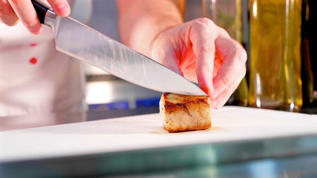 Chef is garnishing tuna fish fillet at restaurant kitchen in slow motion