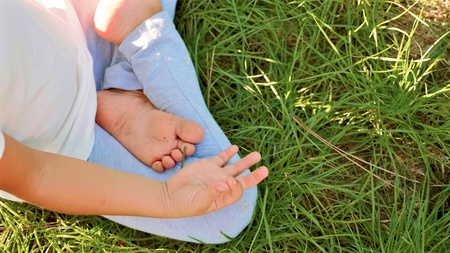 Little cute baby girl meditates on the grass at green summer park.の写真素材