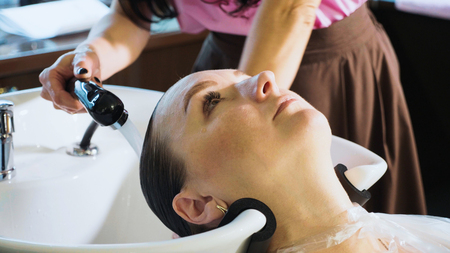 Hairdresser washes womans hair in the beauty studio.の写真素材