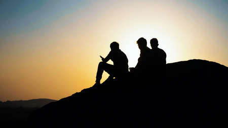 Silhouette group of people admiring the sunset on top of mountainの写真素材