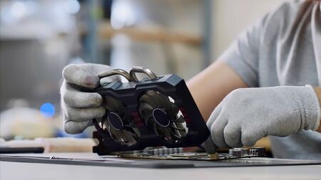 PC repair and maintenance in service center. Repairman fixing the graphics chipset at workshop, closeup. Technician of computer technology at work.の写真素材