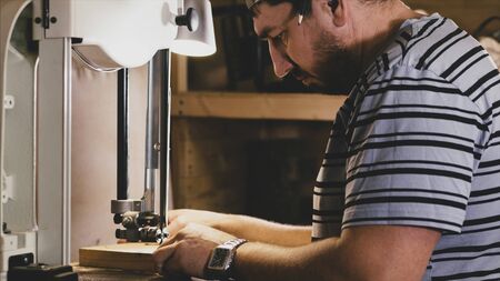 Male carpenter working on milling machine for cutting figure wooden detail