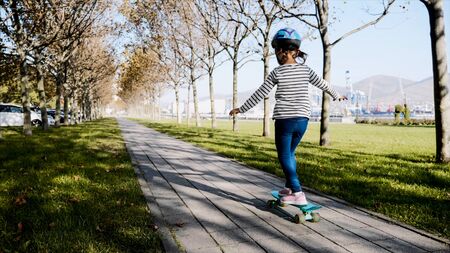 Little girl is slowly skateboarding in protective helmet.の写真素材