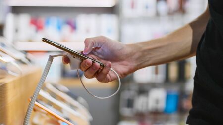 Unrecognizable man chooses a smartphone in an electronics store.の写真素材