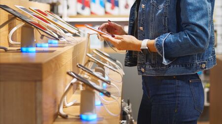 Unrecognizable woman chooses a smartphone in an electronics store.の写真素材